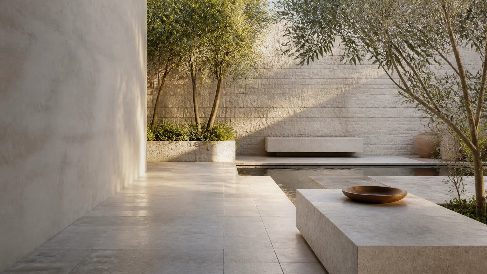 A sheltered limestone courtyard with stone paving, water and mature planting