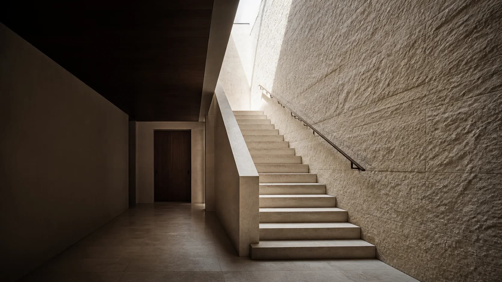 A sculptural limestone staircase beside a richly textured stone wall