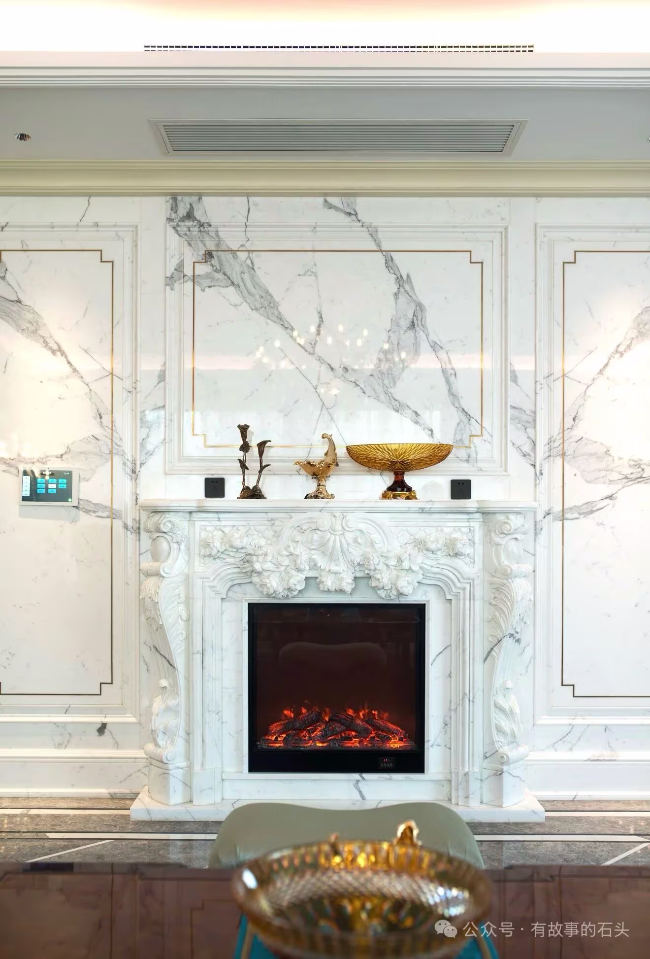 A refined interior with a veined marble wall and sculptural fireplace