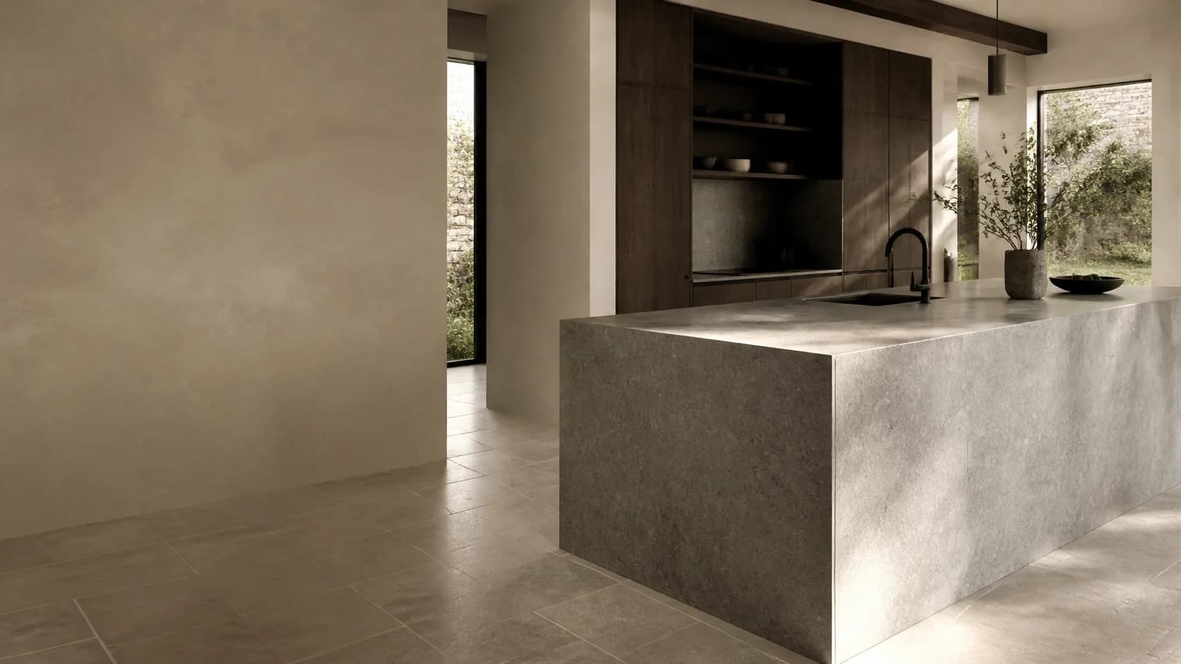 A quiet architectural kitchen arranged around a substantial honed stone island